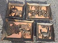 Four copper plates with decorative relief fronts visible