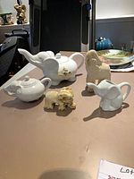 Group shot showing both teapots, creamer, and two figurines