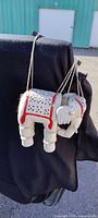 Side view of painted carved wood elephant marionette hanging from strings