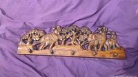 Front view of carved hardwood wall rack showing elephant relief and five peg hooks