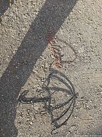 Copper wire "Welcome" sign and black umbrella wall hook shown on ground