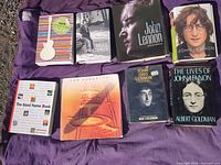 Front covers of all eight books laid out on purple cloth