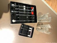 Two trays of cocktail picks and two dice-pattern glasses displayed on table