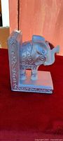 Side view of white elephant bookend on red cloth background
