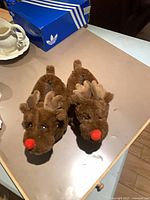 Pair of brown plush reindeer slippers on tabletop