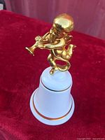 Side view of bone china bell with gilt cherub finial