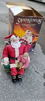 Full view of Santa figurine seated in chair with box behind