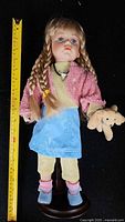 Full view of doll on stand with measuring tape showing height
