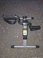 angled view showing full pedal exerciser, pedals, tension knob and warning labels