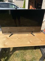 Front view of the 42-inch flat screen TV on wooden table with two V-shaped legs visible.