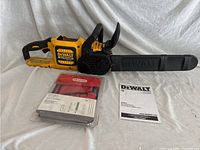 Chainsaw with plastic bar cover in place, Oregon maintenance kit in blister pack, printed DeWalt manual visible