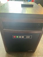 Front view of Duraflame heater showing control panel with power, heat, and fan buttons and an LCD display area.