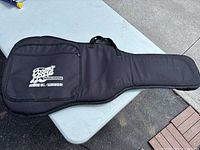 Front view of black padded guitar case showing Cosmo Music Richmond Hill Scarborough logo on front zippered pocket.
