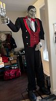 Fully assembled animated butler prop standing 7ft tall in a black tuxedo with red vest and bow tie, holding a candelabra