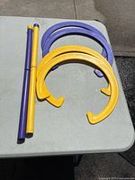 Close-up of yellow and purple plastic horseshoe rings along with two poles for horseshoe game.