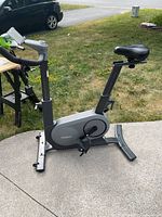 Full view of the Renpho exercise bike on a concrete patio showing the gray frame, seat, pedals, and front and rear stabilizers.