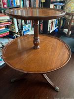 Full view of two-tier round pedestal table showing tiers, column and tripod legs