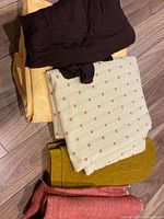 Stack of five folded fabrics in various colors and textures