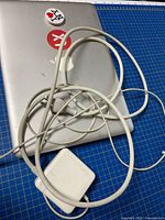 Closed MacBook Pro with decals and coiled MagSafe charger on top