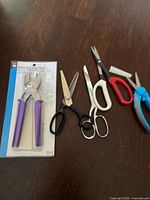 Group view of packaged Dritz snap pliers and five pairs of scissors