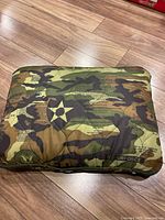 Full view of sealed camouflage zip bag containing jacket with star insignia visible