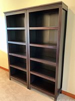 Two matching tall wooden bookshelves with dark red stain positioned side-by-side showing overall front and side view.