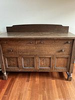 Full front view of the antique walnut buffet showing three drawers on top and four cabinet doors below with wooden knobs.