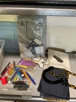 Overview of the beading craft lot showing beads, spool of red thread, plastic containers, adhesive sheets, black and tortoiseshell purse handles, fabric patterns, and bead design board.