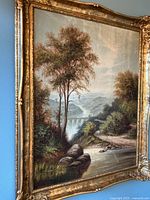 Full view of gilt framed oil painting depicting a river landscape with aqueduct and trees