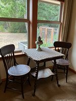 Entire set includes the 26x26x28.5 inch table with two chairs and oil lamp, shown near window with outdoor background.