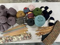 Overview of yarn skeins in multiple colors, bamboo and metal knitting needles, needle cases