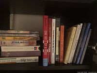 Shelf showing stacked sealed DVDs and CDs left, row of books right