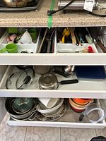 Three-drawer cabinet showing utensils, pans, lids, colanders, ramekins