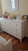 Front view of white eight-drawer dresser with items on top