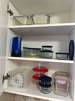 Cabinet showing full assortment of plastic and glass containers, basket, microwave cover, flashlight