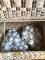 Two plastic bags of golf balls inside wicker basket