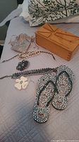 All lot items on bed: flip flops, jewelry pieces, wooden box, pouch
