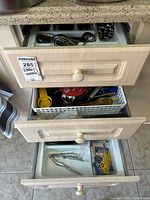 Three drawers showing cutlery tray, utensil basket and lower drawer contents