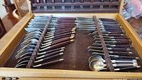 Drawer view showing rows of wood-handled flatware pieces