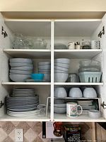 Entire cabinet contents showing stoneware, porcelain, glass bowls and glasses