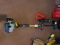 Ryobi string trimmer, hedge trimmer and extension cord on floor