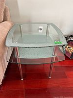Front view of two-tier glass side table showing textured top shelf and metal legs