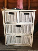 Front view of white wood cabinet with four wicker drawers