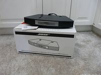 Changer resting on its original box showing front grille and top handle