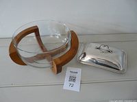 Glass bowl in wood stand next to silver plated cheese dish lid
