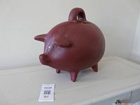 Side view of large pink ceramic piggy bank on surface
