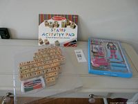 Stamp activity pad, tray of wooden stamps and boxed magnetic doll set on table