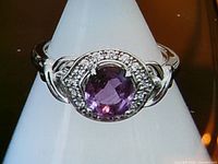 Full view of sterling silver ring on mandrel showing purple stone and clear halo