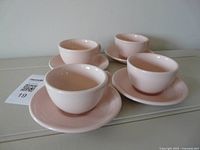 Four pink coffee cups each seated on its saucer