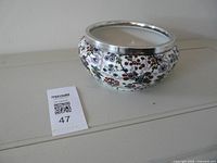 Full view of floral bowl beside lot tag